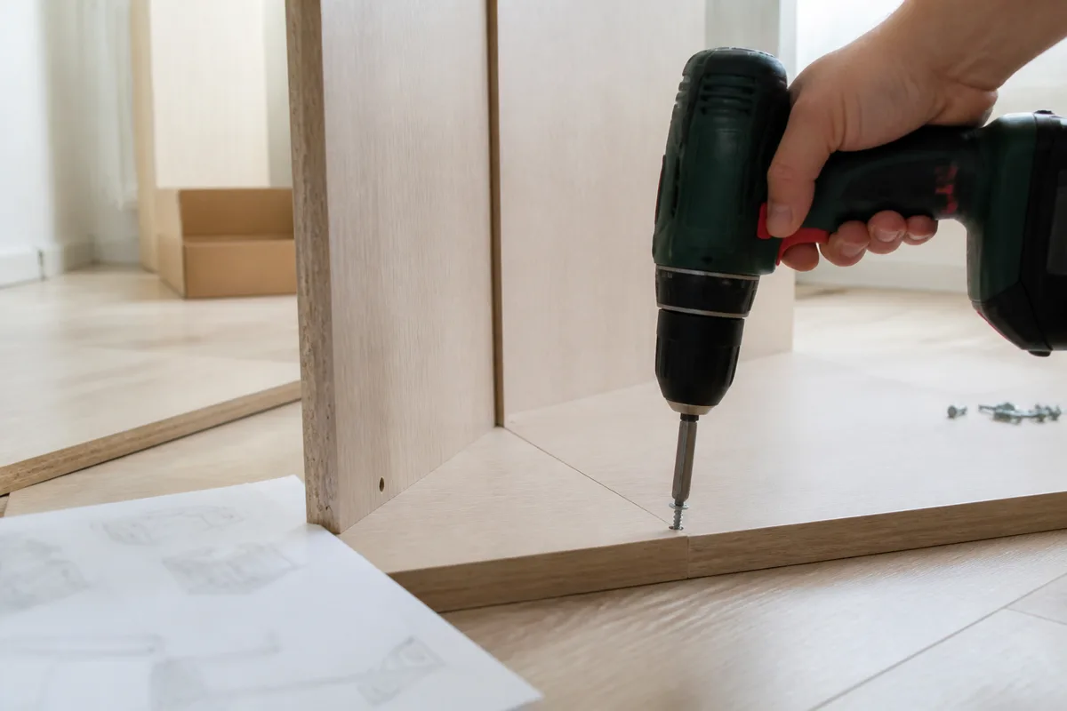 Perceuse-visseuse sans fil utilisée pour assembler un meuble en bois à la maison