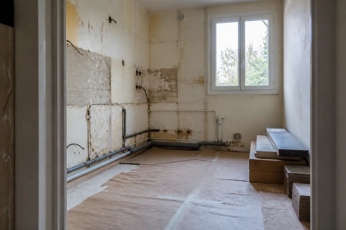 Rénovation pièce par pièce d'une cuisine en cours de travaux avec réseaux apparents et matériaux protégés